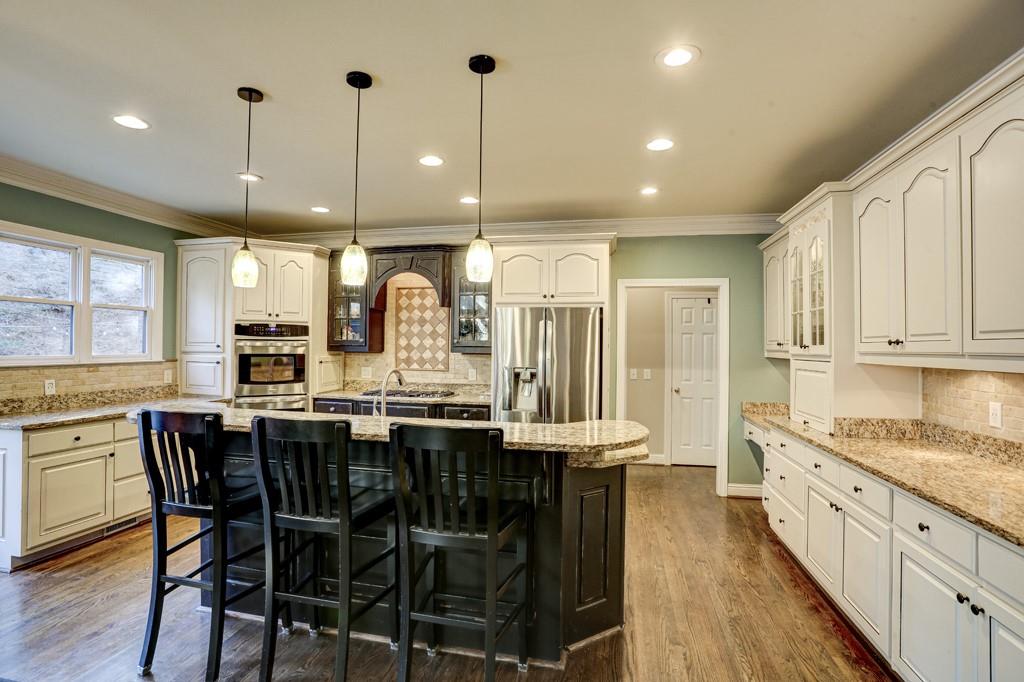 5940 Whitestone Lane Suwanee, GA 30024 - Photo 20 of 63 a kitchen with stainless steel appliances kitchen island granite countertop a table chairs sink and cabinets