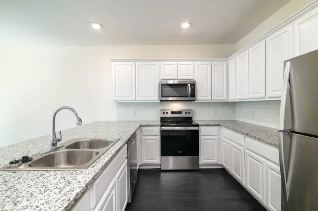 a kitchen with stainless steel appliances granite countertop a sink stove and refrigerator