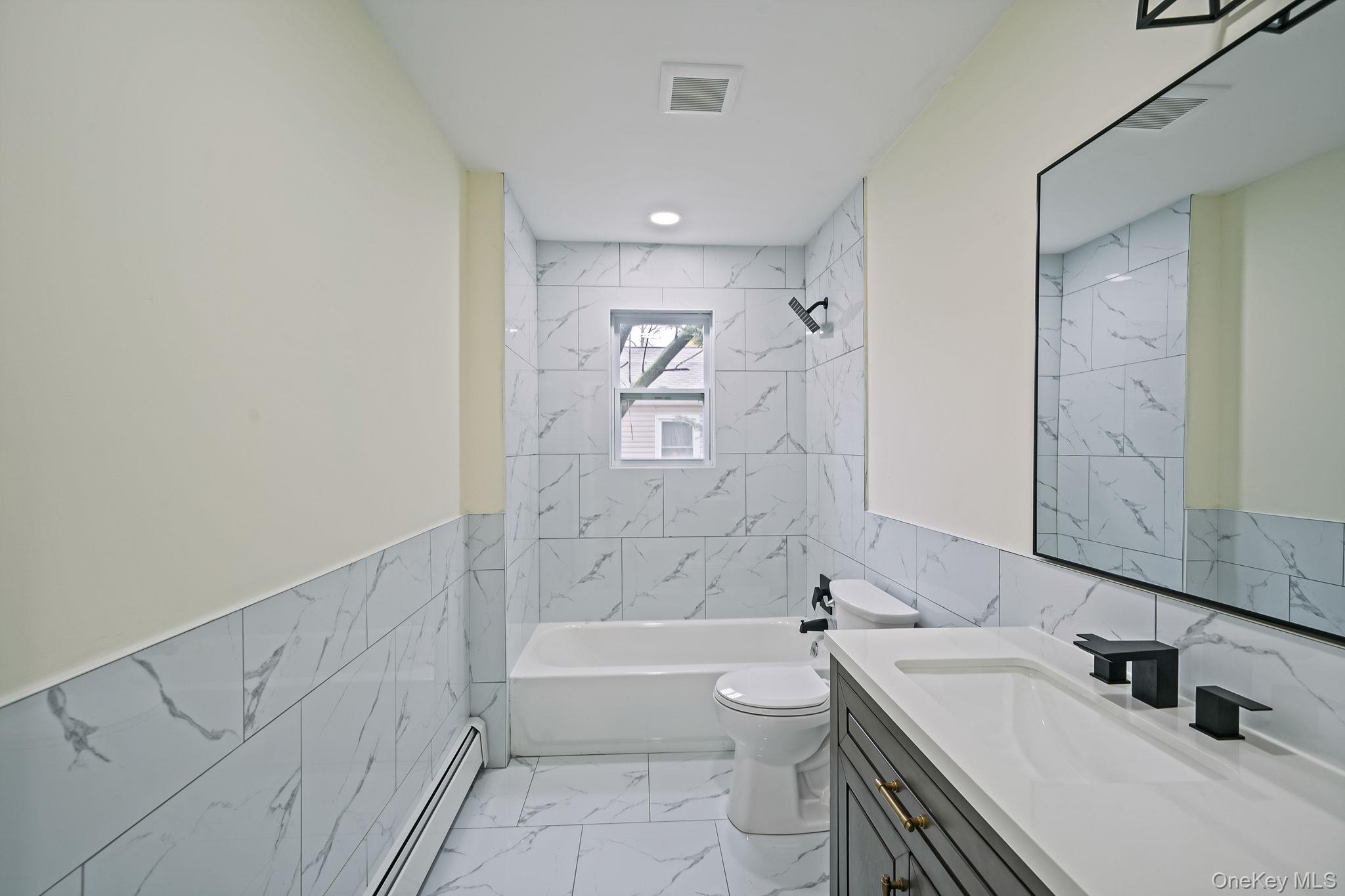 50 7th Street St. James, NY 11780 - Photo 12 of 25 a bathroom with a bathtub shower sink mirror and toilet