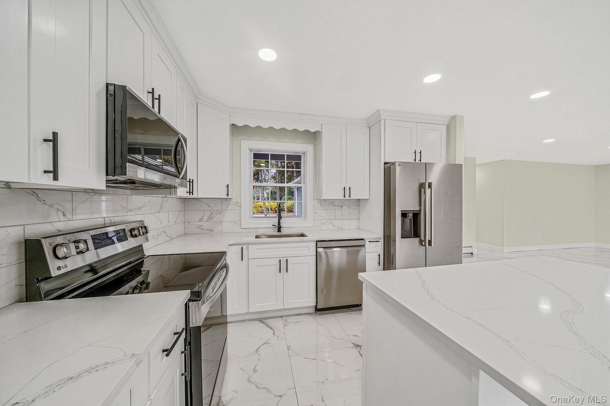 50 7th Street St. James, NY 11780 - Photo 5 of 25 a kitchen with stainless steel appliances a stove sink microwave refrigerator and cabinets