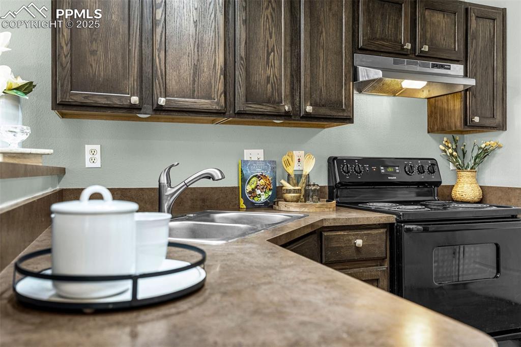 3254 Apogee View Colorado Springs, CO 80906 - Photo 14 of 28 a kitchen with a sink and a stove with wooden cabinets