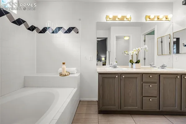 a bathroom with a granite countertop sink a mirror a vanity and a bathtub
