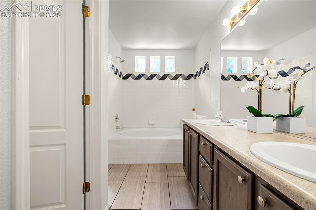 3254 Apogee View Colorado Springs, CO 80906 - Photo 24 of 28 a bathroom with a granite countertop sink a mirror a vanity and a bathtub