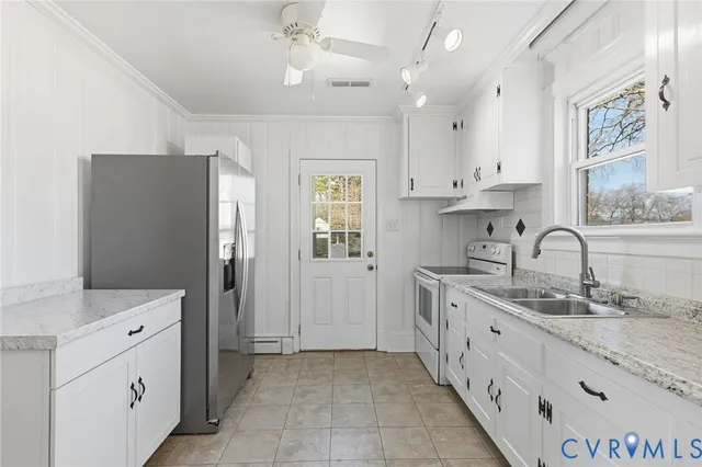 a kitchen with stainless steel appliances granite countertop white cabinets sink and window