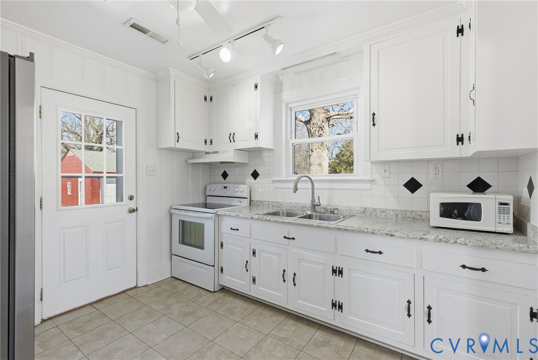 5116 Alberene Road Richmond, VA 23224 - Photo 5 of 20 a kitchen with stainless steel appliances granite countertop white cabinets sink and window
