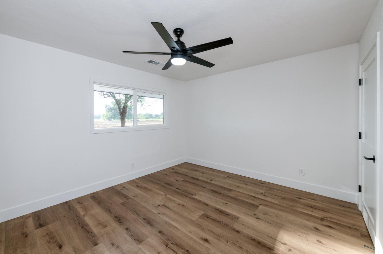 545 North Rio Vista Avenue Sanger, CA 93657 - Photo 33 of 46 an empty room with wooden floor ceiling fan and windows