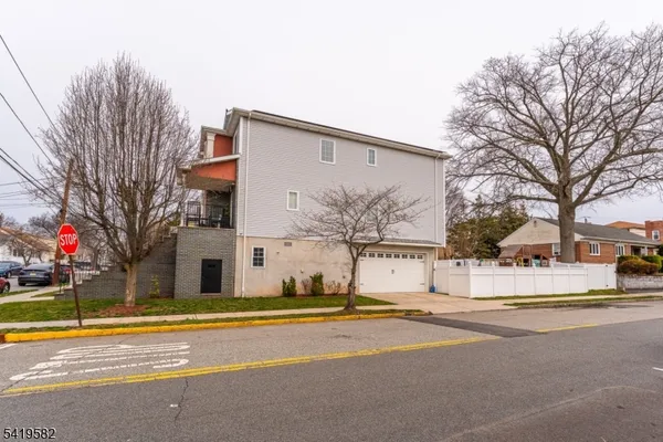 a view of a white house with a large tree