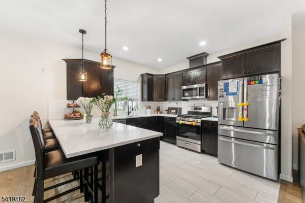 a kitchen with granite countertop a sink stainless steel appliances and chairs