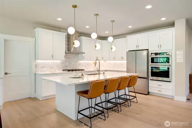 a kitchen with stainless steel appliances kitchen island granite countertop a table chairs and a refrigerator