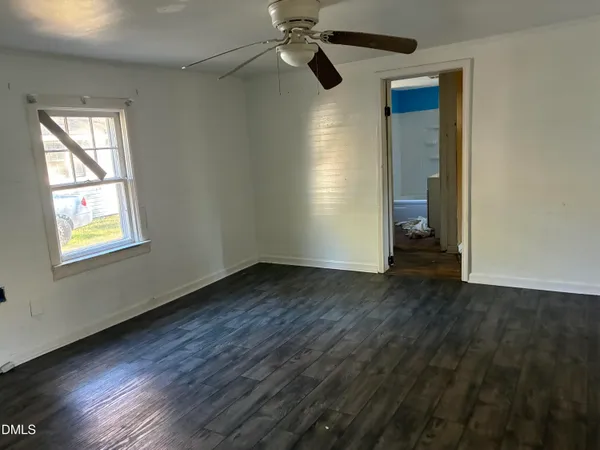 an empty room with wooden floor cabinet and windows