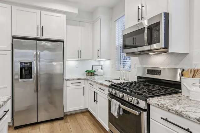 a kitchen with stainless steel appliances granite countertop a stove top microwave and refrigerator