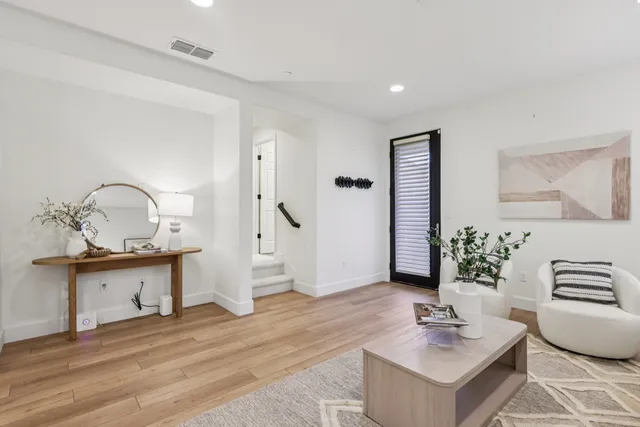 a view of living room kitchen with stainless steel appliances furniture a mirror and wooden floor