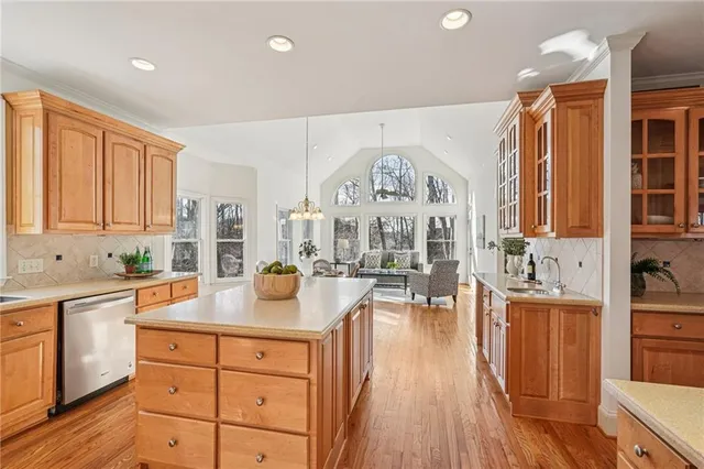 a kitchen with stainless steel appliances granite countertop a stove a sink dishwasher and white cabinets with wooden floor