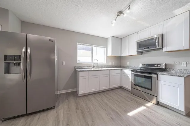 a kitchen with stainless steel appliances granite countertop a stove a sink and a refrigerator