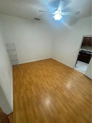 a view of a room with wooden floor and chandelier fan
