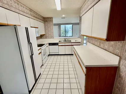 a large white kitchen with sink a refrigerator and a stove