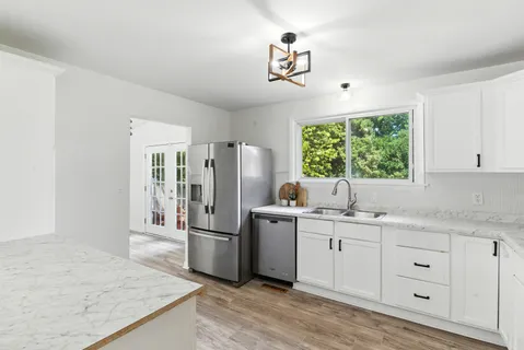 a kitchen with white cabinets and window