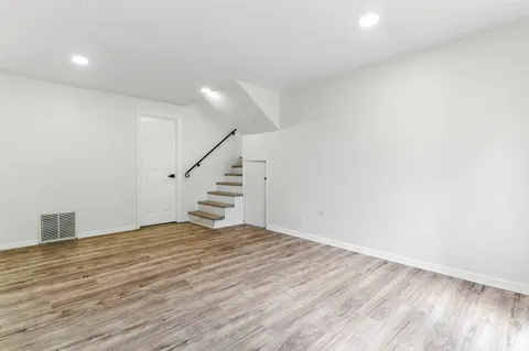 a view of an empty room with wooden floor and stairs