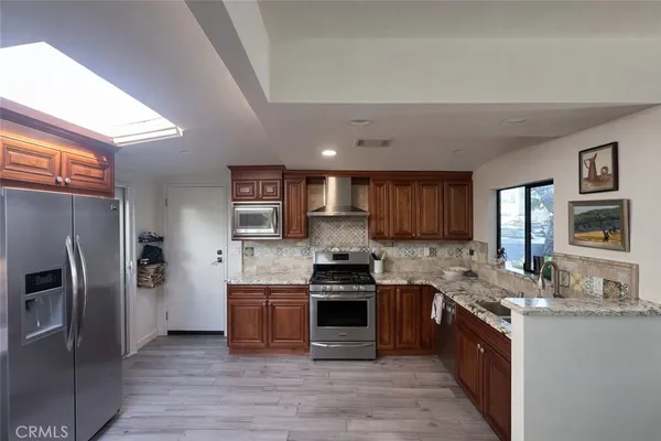 a kitchen with stainless steel appliances granite countertop a refrigerator and a stove top oven