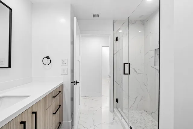 a spacious bedroom with a bed and glass walk in closet