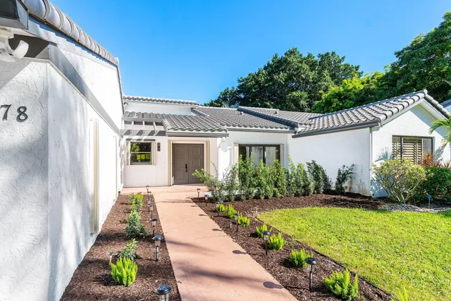 a kitchen with stainless steel appliances kitchen island granite countertop a refrigerator a sink dishwasher a dining table and chairs with wooden floor