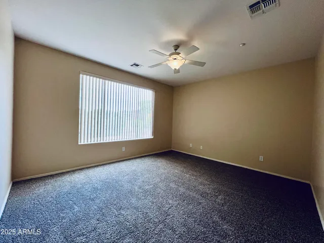 an empty room with windows and ceiling fan