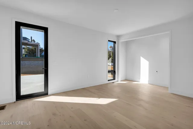 a view of an empty room with window and wooden floor