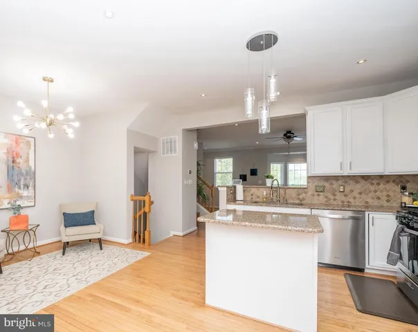 a kitchen with kitchen island stainless steel appliances a dining table chairs sink and stove