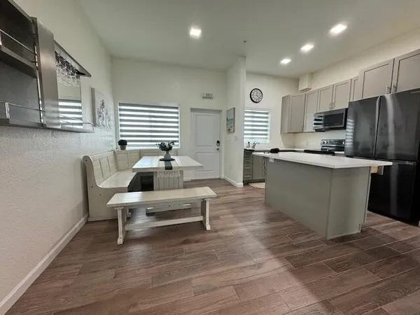 a living room with stainless steel appliances kitchen island granite countertop a sink dishwasher a stove and a refrigerator with wooden floor