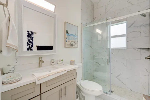 a bathroom with a granite countertop sink a toilet and shower