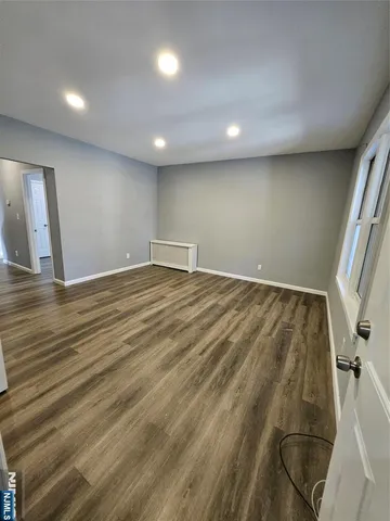 an empty room with wooden floor and entrance