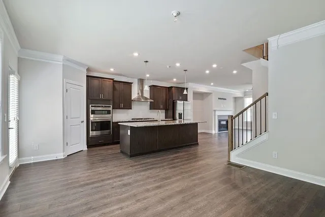 a large kitchen with stainless steel appliances kitchen island granite countertop a large counter top and wooden floors