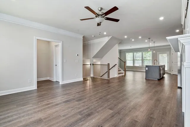 a view of an empty room with wooden floor and a ceiling fan