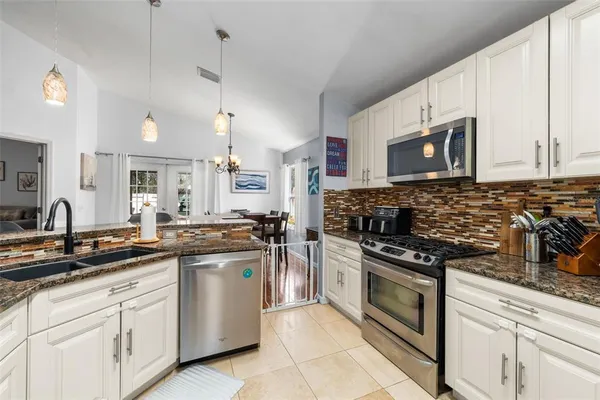 a kitchen with stainless steel appliances granite countertop a sink a stove and cabinets