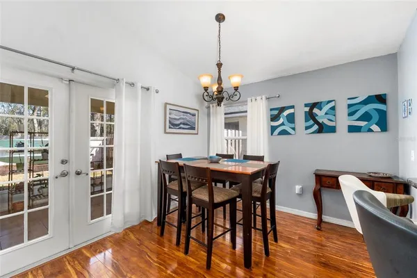 a dining room with wooden floor a chandelier a wooden table and chairs