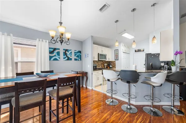 a view of a dining room with furniture a kitchen and chandelier