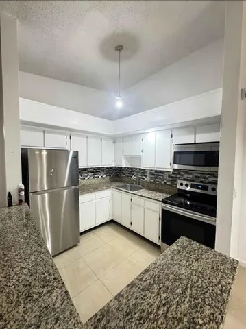 a kitchen with stainless steel appliances kitchen island granite countertop a refrigerator and a stove top oven