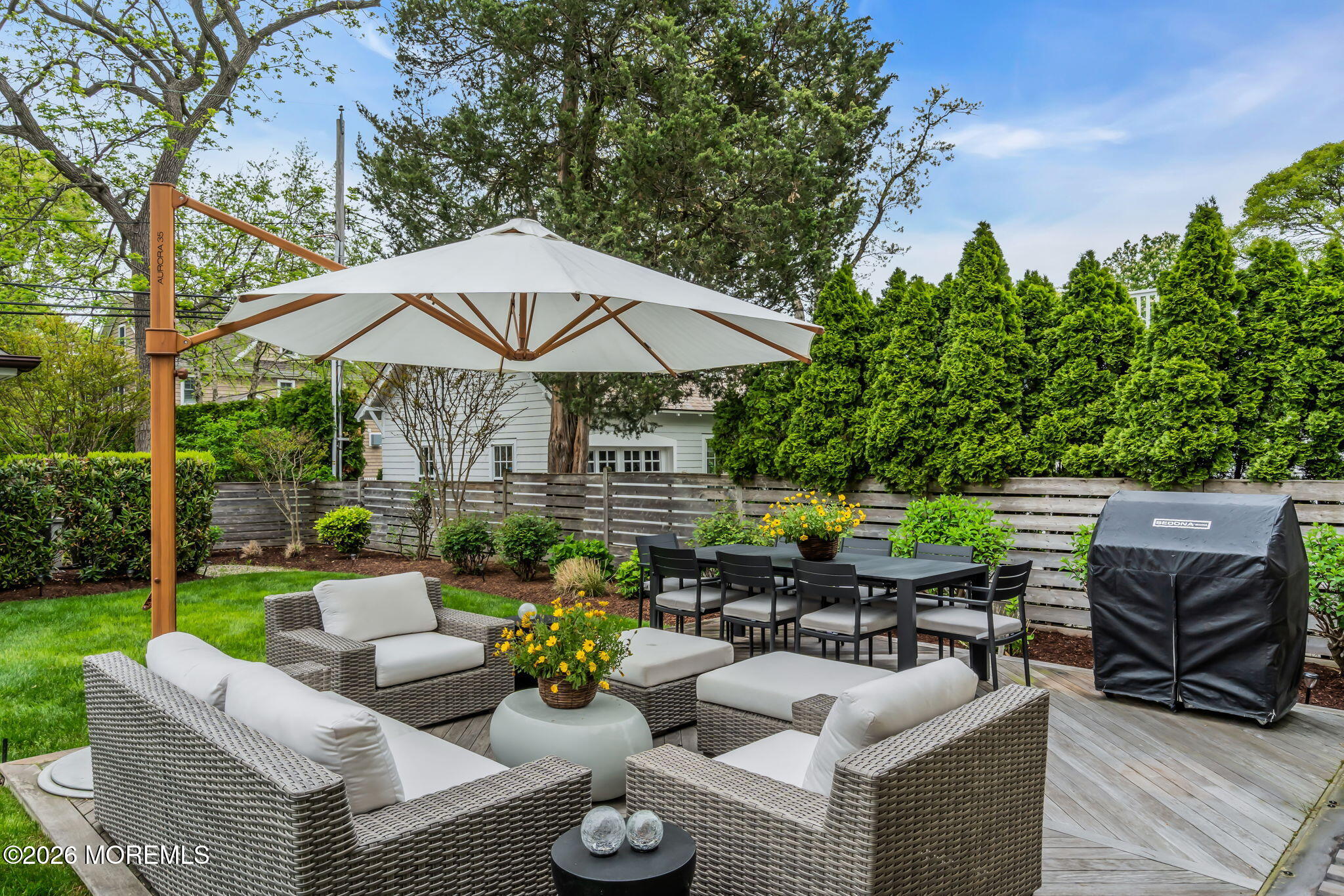 218 Worthington Avenue Spring Lake, NJ 07762 - Photo 47 of 51 a view of a patio with couches table and chairs under an umbrella with a garden