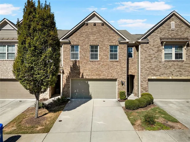a view of a house with a yard and large tree