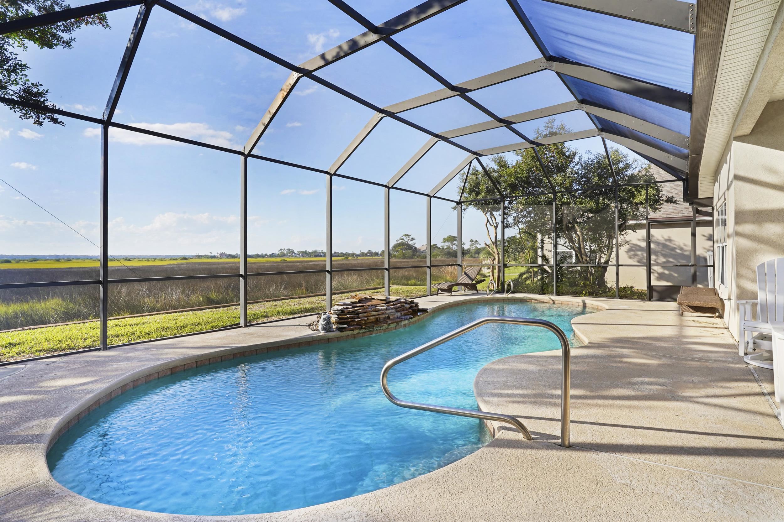 Swimming pool with a sunroom, glass enclosure, and a patio area