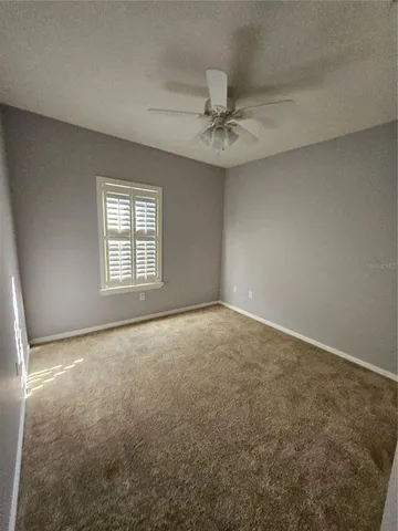 an empty room with a window and a fan