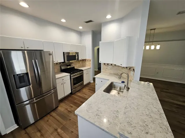 a kitchen with stainless steel appliances granite countertop a refrigerator stove microwave and sink