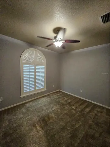 a view of an empty room with a chandelier fan