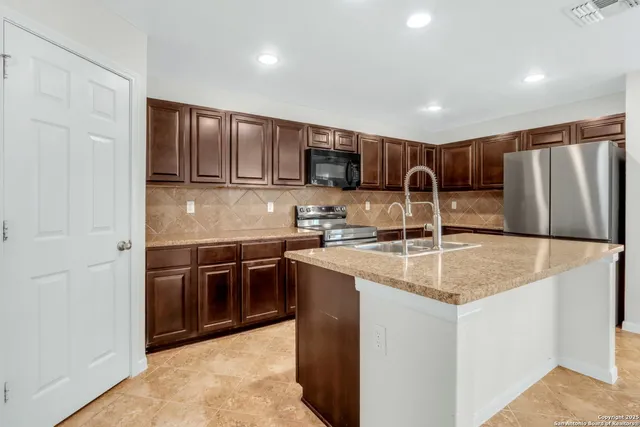 a kitchen with stainless steel appliances granite countertop a sink a stove and a refrigerator