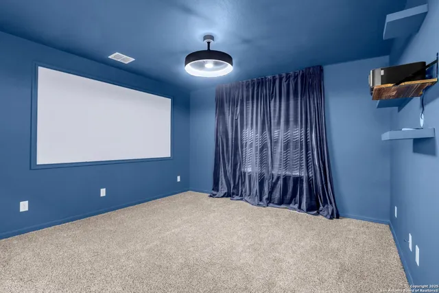 a view of an empty room and chandelier fan