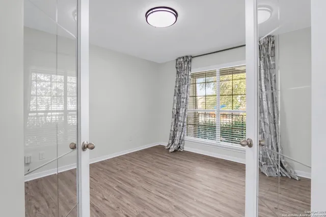 a view of an empty room with wooden floor and a window