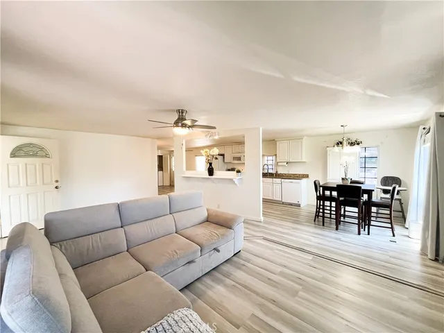 a living room with furniture wooden floor and kitchen view