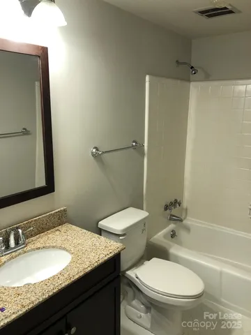 a bathroom with a granite countertop toilet sink and mirror