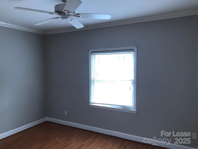 an empty room with wooden floor ceiling fan and window