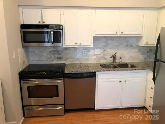 a kitchen with granite countertop white cabinets and stainless steel appliances